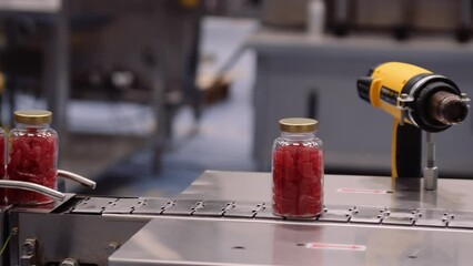 Bottled red gummy supplements on conveyor belt - multivitamin manufacturing