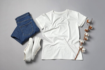 Stylish t-shirt, jeans and sneakers on light grey background, flat lay