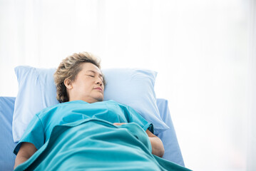 Asian senior or elderly old woman patient lie down handle the rail bed with hope on a bed in the hospital, old lady is sick and lying on the patient bed, recovering on saline drip solution