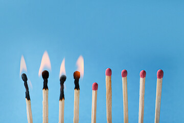 Burning and whole matches on light blue background, closeup. Stop destruction by breaking chain...