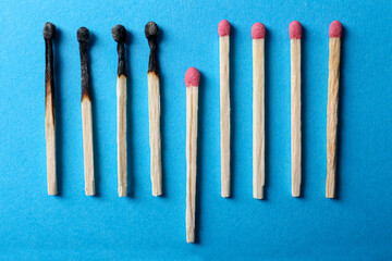 Burnt and whole matches on light blue background, flat lay. Stop destruction by breaking chain reaction concept