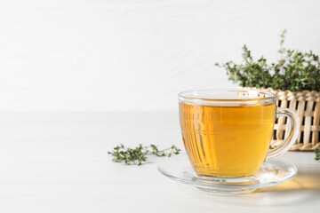 Aromatic herbal tea with thyme on white wooden table, space for text