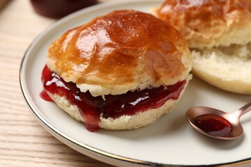 Freshly baked soda water scones with cranberry jam on wooden table, closeup