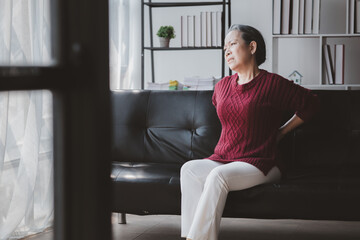 Senior woman sitting in the living room at home and showing body aches, aging sickness, body aches of elderly people, organ degeneration.