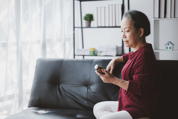 Senior woman sitting in the living room at home and showing body aches, aging sickness, body aches of elderly people, organ degeneration, taking prescription drugs.