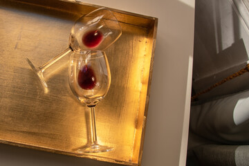 Used wine glasses, two half empty glasses of red wine on a golden tray background
