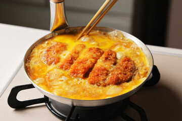 鍋で調理しているかつ丼