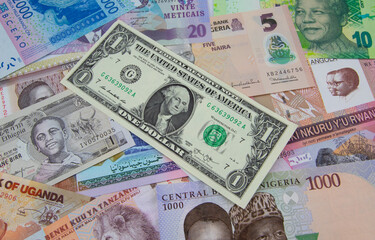 A collection of African currencies with a 1 American dollar bank note sitting on top