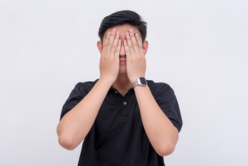 A man covers his eyes, refusing to look. Isolated on a white background. See no evil or concept of...