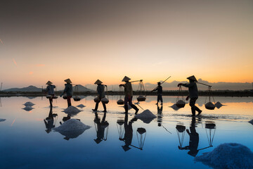 the women are working on salt field at dawn. Salt field Hon Khoi in Nha Trang, Viet Nam. Workers...