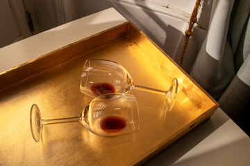 Used wine glasses, two half empty glasses of red wine on a golden tray background