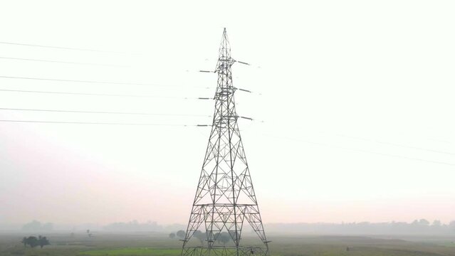 Slow pull back of electricity pylon tower on hazy, misty Bangladesh countryside sunrise skyline