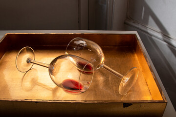 Used wine glasses, two half empty glasses of red wine on a golden tray background
