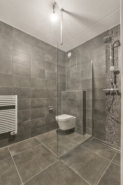 a modern bathroom with grey tiles on the walls, and a white toilet in the corner of the shower stall