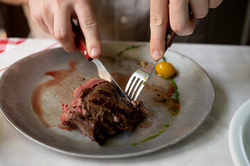 Close-up of plate with perfect rare cooked steak and male hands on table.Man eating meat.People and food concept.