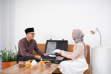 Portrait of Muslim couple preparing suitcase for back to hometown (mudik) before Idul FitriEid...