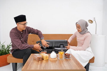 Portrait of Muslim couple preparing suitcase for back to hometown (mudik) before Idul FitriEid...