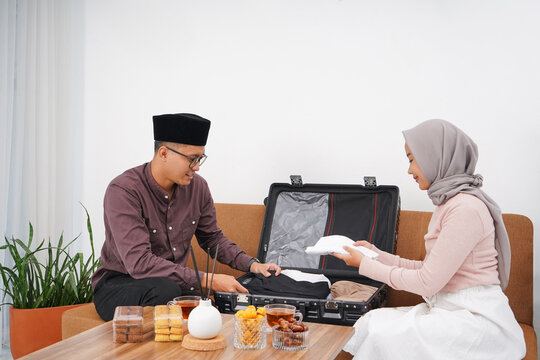 Portrait of Muslim couple preparing suitcase for back to hometown (mudik) before Idul FitriEid al-Fitr at home