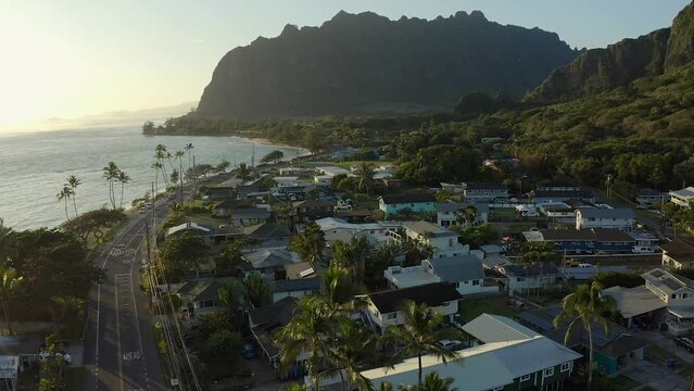 Aerial shot of the calm village of Kaaawa Hawaii during sunrise going toward the Kualoa Ranch,