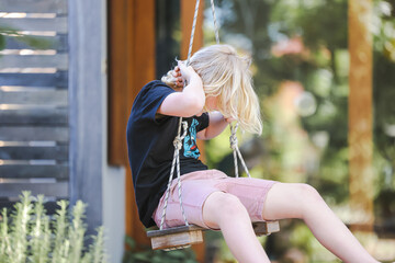 Boy spinning on backyard swing on a tranquil patio on a beautiful spring day