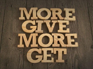 More you give more you get, text words typography written with wooden letter, life and business motivational inspirational