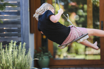 Boy spinning on backyard swing on a tranquil patio on a beautiful spring day