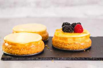 Mini cheesecakes with fresh berries topping, close-up on light grey background
