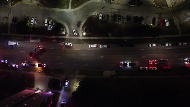 Top-down aerial footage captures emergency services intervening on a blocked highway during nighttime, highlighting their quick response and teamwork.