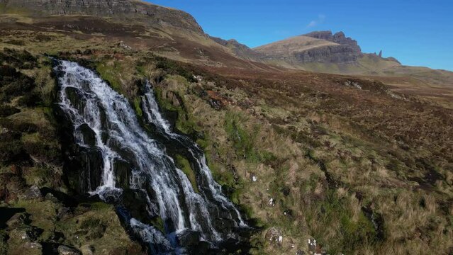 Pan across Scottish Highland waterfall with The Storr on the horizon at Brides Veil Falls Trotternish Isle of Skye