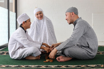 Cheerful muslim family with children reading Quran together and discuss about Islam after praying...