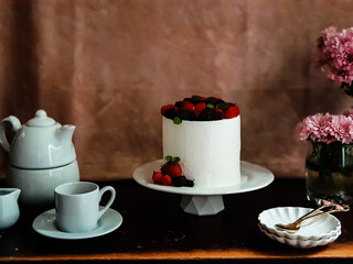 Selective focus of Decorated by strawberries raspberries white naked cake, rustic style for weddings, birthdays and events. On brown background. Selective focus. In kitchen