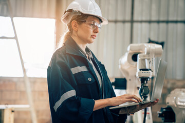 Female engineers or worker is controlling robot arm machine welding steel, worker using forcing...