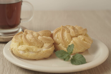 Kue Soes or choux à la crème on white plate. Perfectly puffed and filled with a creamy filling, this classic French dessert is sure to delight. Selective Focus , Closeup