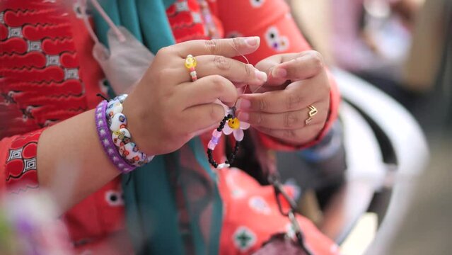 an Indonesia woman is working on beads jewellery at her own workplace.