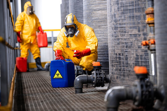 Trained factory workers carefully handling toxic and dangerous biohazardous waste in chemicals factory.