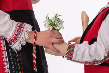 Bulgarian kids boy and girl in traditional folklore costumes with spring flowers snowdrop and...