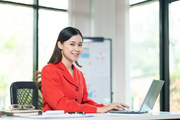 Portrait of pretty cheerful girl smiling while working on laptop in office