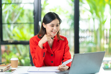 Portrait of pretty cheerful girl smiling while working on laptop in office