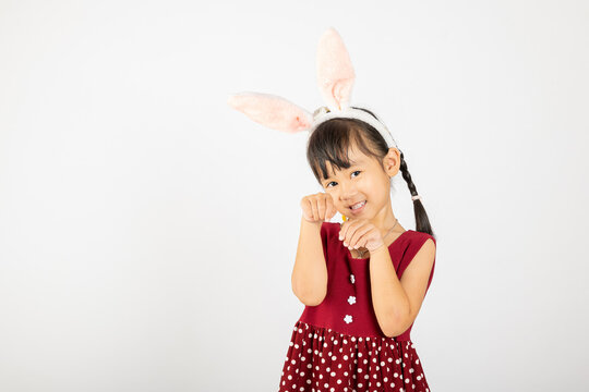 Happy Easter Day. Smile Asian little girl wearing bunny ears make hands act like a rabbit studio shotr isolated on white background with copy space, Easter eeasonal sale and discount