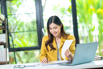 Portrait of pretty cheerful girl smiling while working on laptop in office