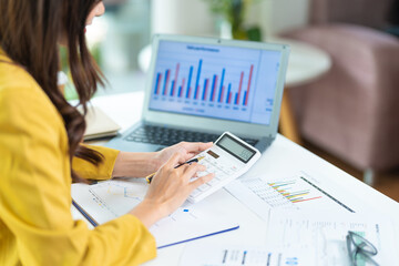 Portrait of asian business woman paying bills online with laptop in office. Beautiful girl with computer and checkbook, happy paying bills. Startup business financial calculate account concept