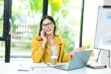 Happy business woman talking on mobile phone while analyzing weekly schedule in her notebook