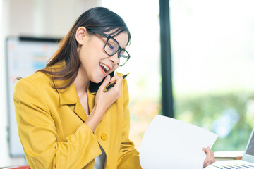 Happy business woman talking on mobile phone while analyzing weekly schedule in her notebook