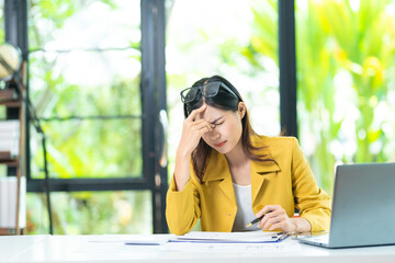 Fototapeta premium Asian women are stressed while working on laptop, Tired asian businesswoman with headache at office, feeling sick at work, copy space