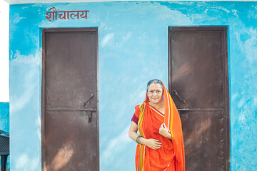 Portrait of of happy senior indian woman standing outside public toilet solves the problem for many...