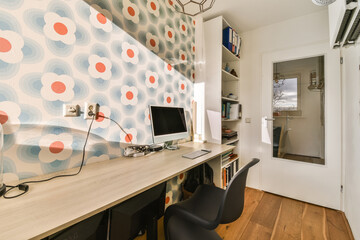 a room with a desk, chair and computer on the table in front of an open door that leads to another...