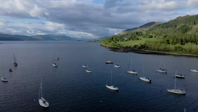 4k aerial drone footage zooming out over docked sailboats in loch  lake near scottish highlands scotland