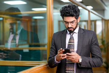 Young indian entrepreneur using smartphone at office