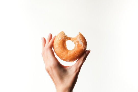 hand holding sweet delicious glazed donut on white background.