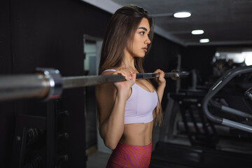 Fototapeta na wymiar Sexy athletic sport girl with perfect fitness body doing workout hard training with bar in the gym